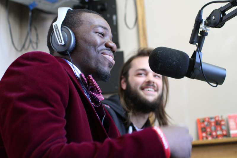 a man wearing headphones and smiling next to a microphone