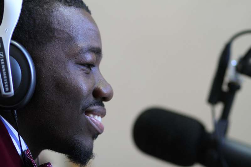 a man smiling at a microphone