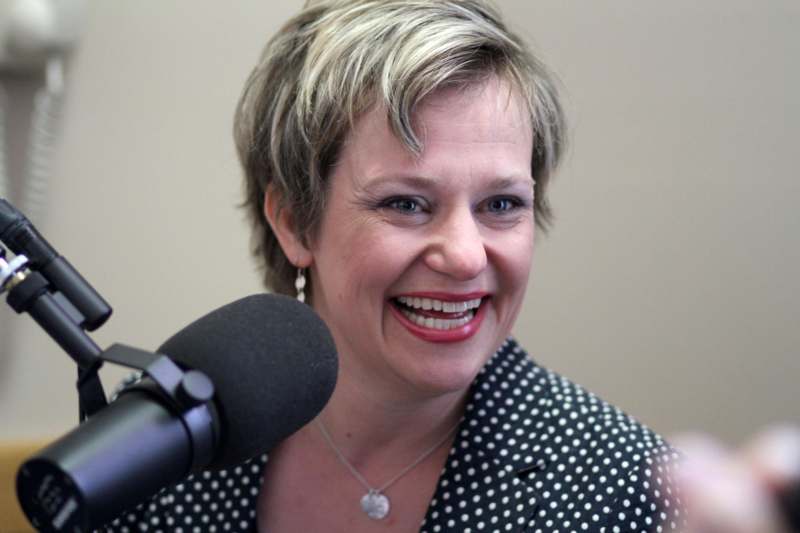 a woman smiling at a microphone