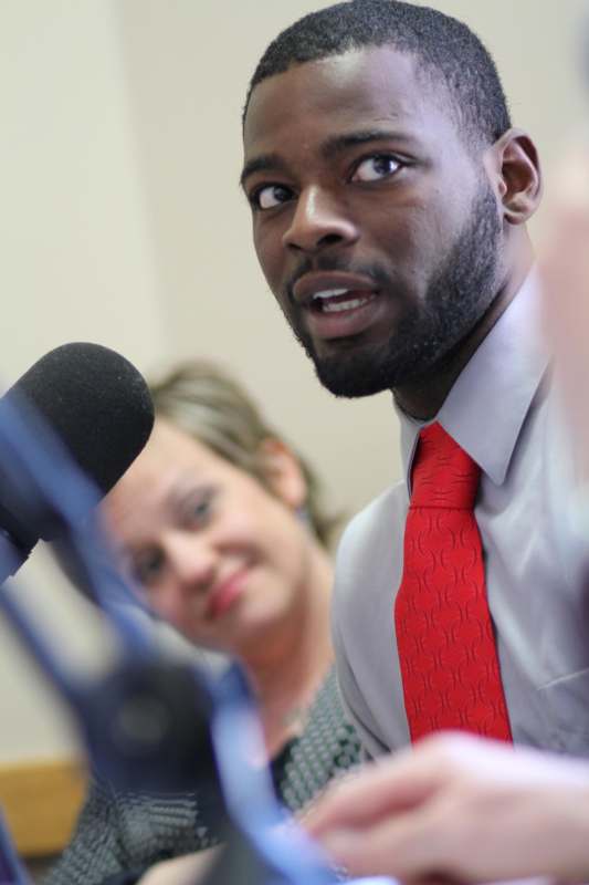 a man in a red tie speaking into a microphone