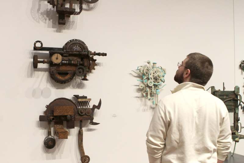 a man looking at a wall with various pieces of metal