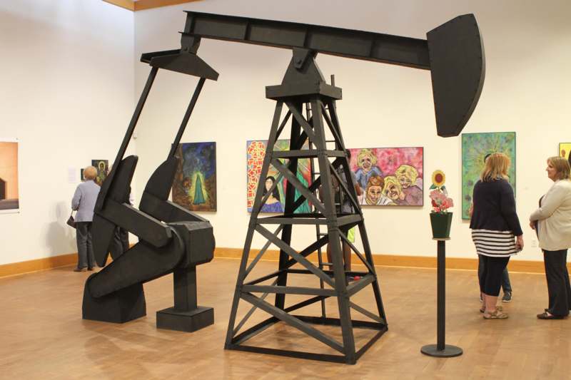 a large metal oil rig in a room with paintings on the wall