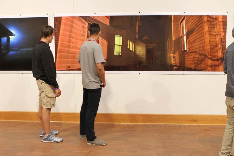 a group of men looking at a painting on a wall