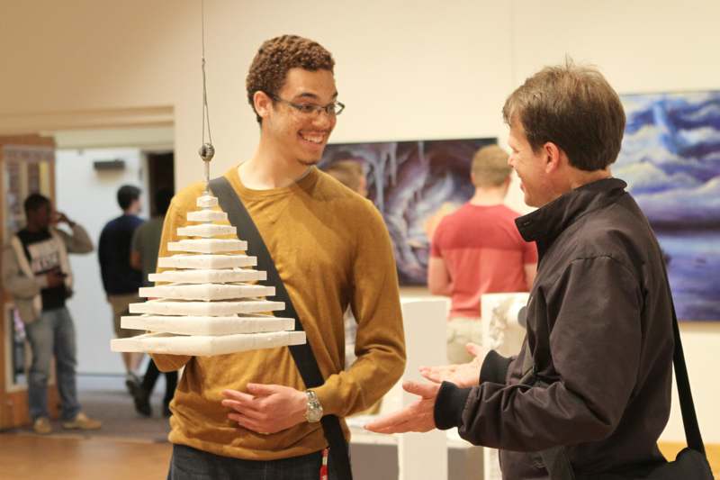 a man holding a pyramid made of white objects