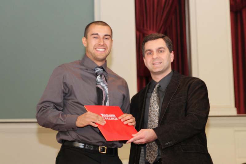 a man holding a red folder with another man smiling