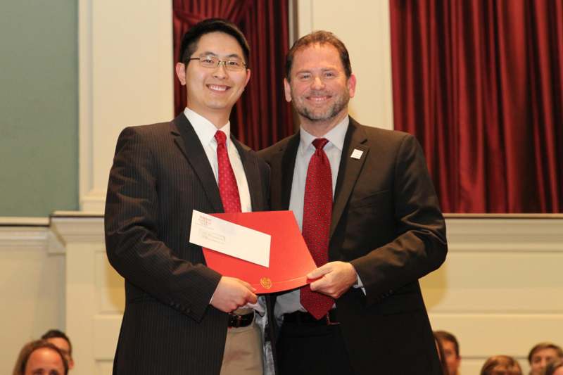 a couple of men in suits holding a red folder