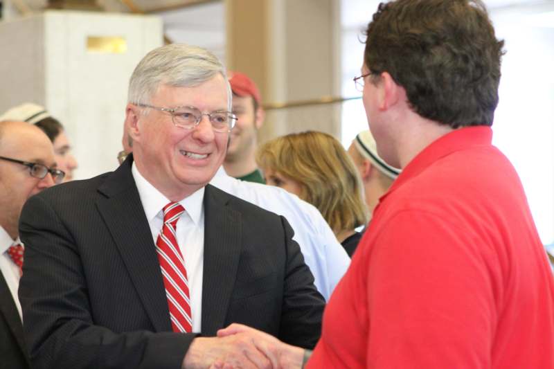 a man in a suit shaking hands with another man in a red shirt