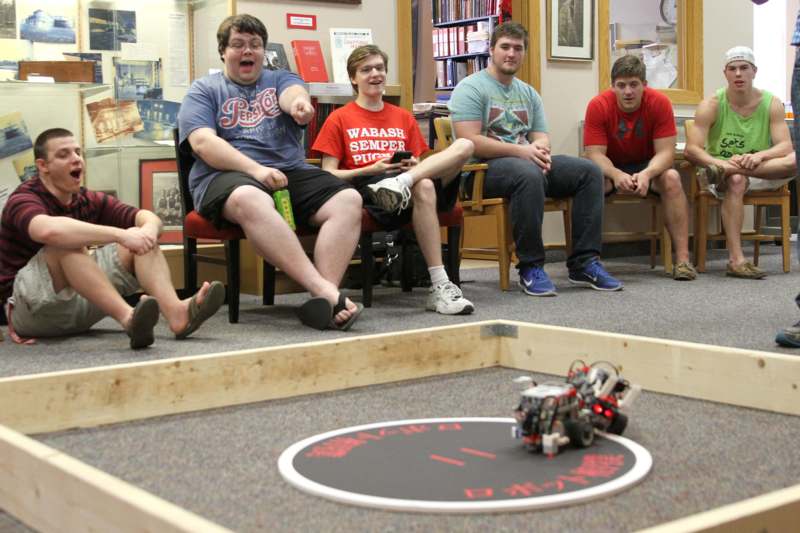 a group of people sitting in chairs and playing with a robot