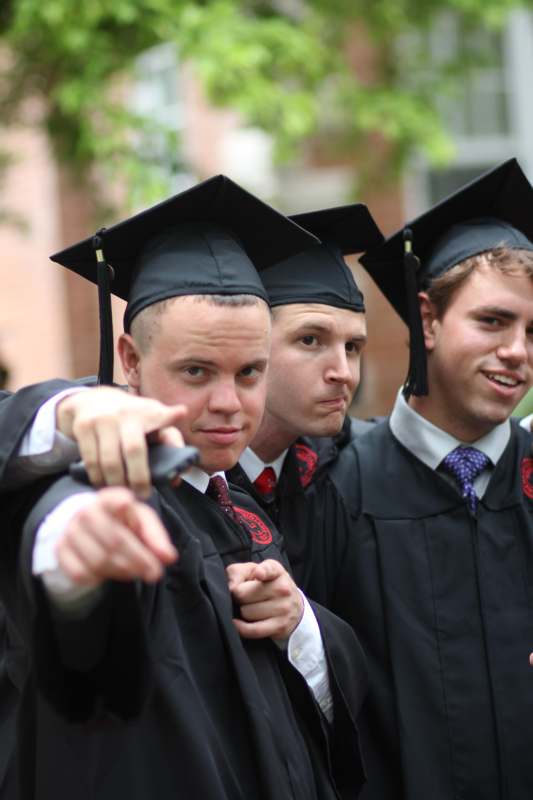 a group of men in graduation gowns pointing at something