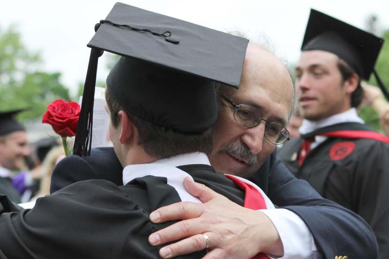 a man hugging a man in a graduation cap