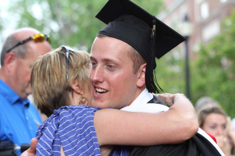 a man in a graduation cap and gown hugging a woman