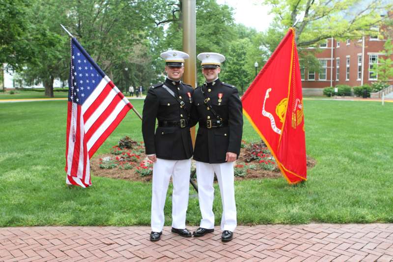 two men in military uniforms standing in front of flags