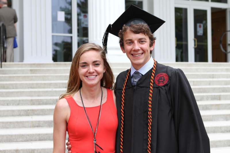 a man and woman in graduation gowns and cap standing in front of a building