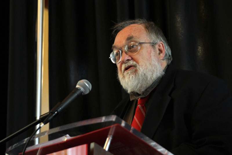a man with a beard and glasses speaking into a microphone