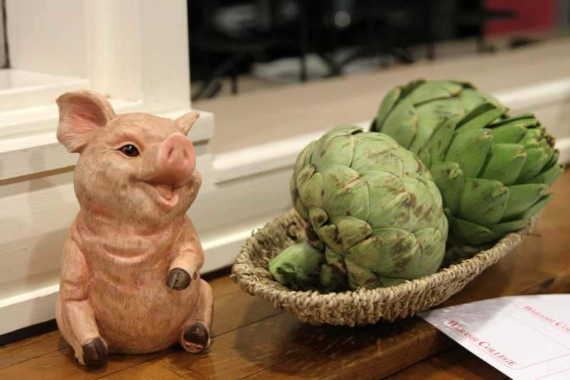 a pig figurine and a basket of artichokes
