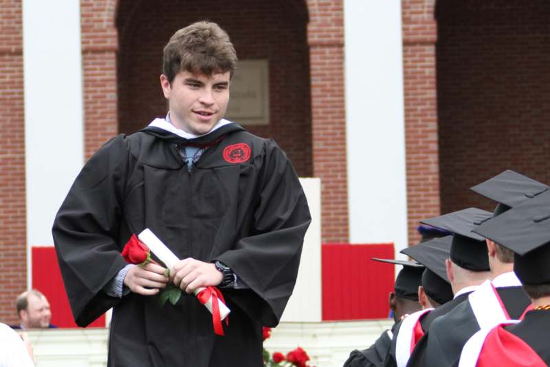 a man in a graduation gown holding a diploma