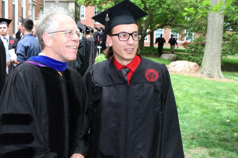 a man in a cap and gown standing next to a man in a cap and gown