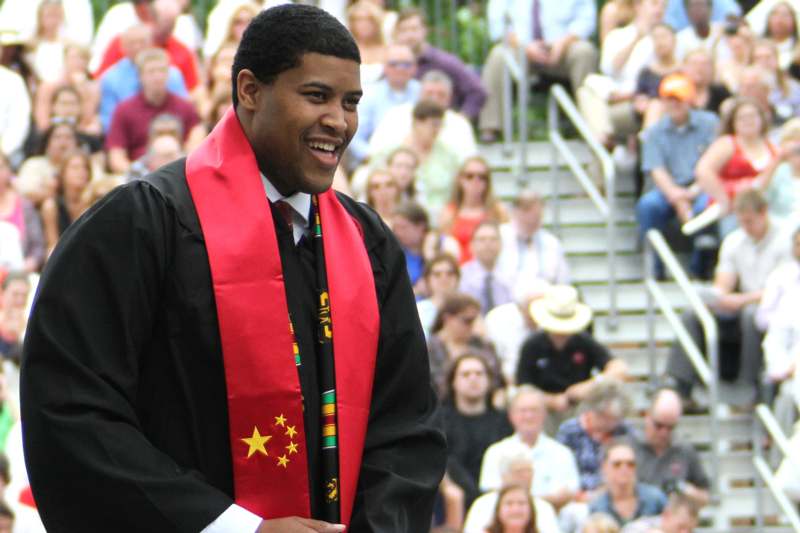 a man wearing a graduation gown and a red sash