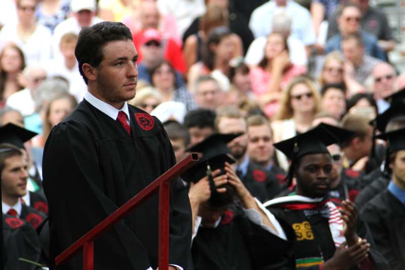 a man in a graduation gown standing on a red railing