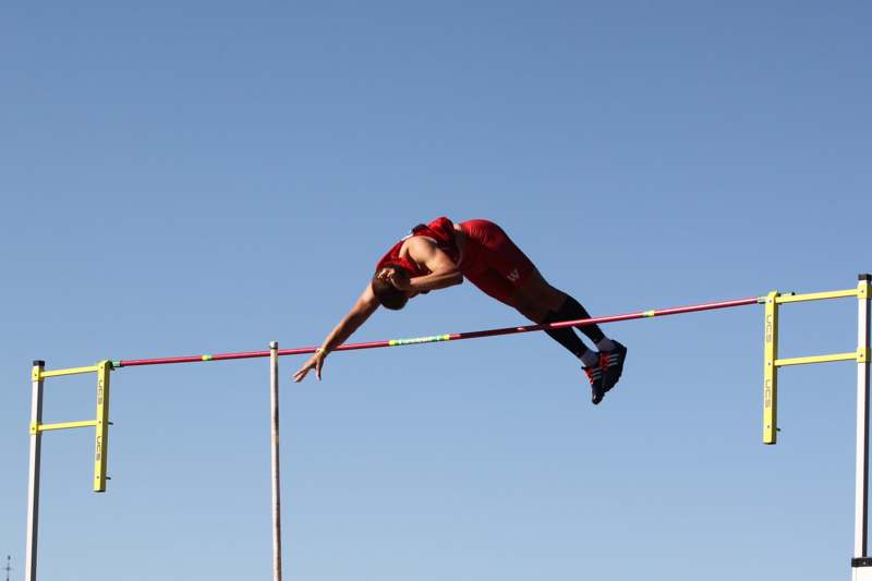a person in red shorts jumping over a bar