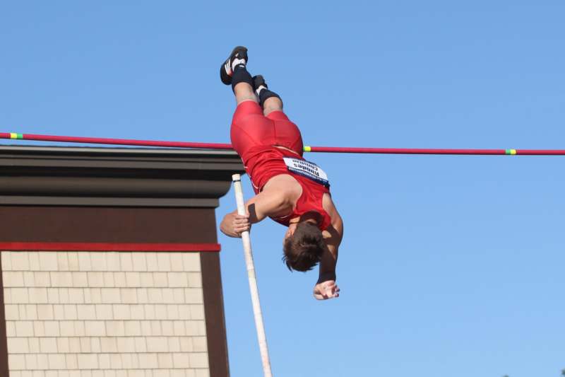 a man in red shorts jumping over a bar