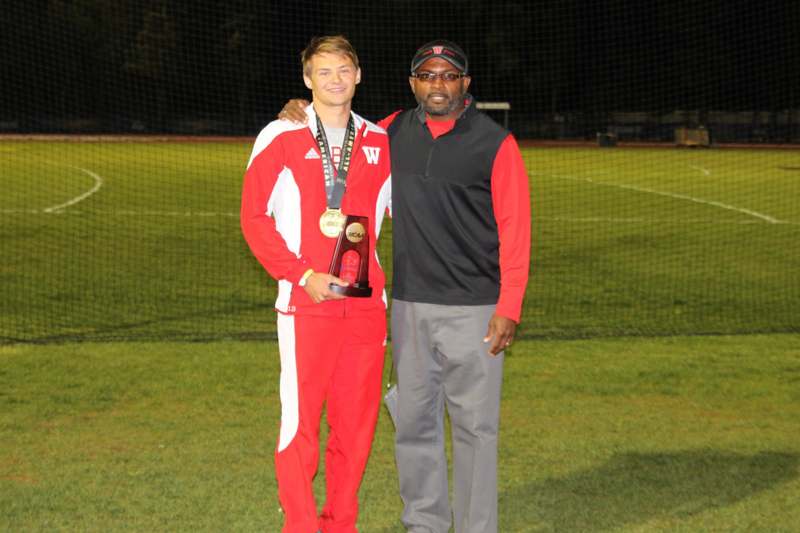 a man standing next to a man holding a trophy