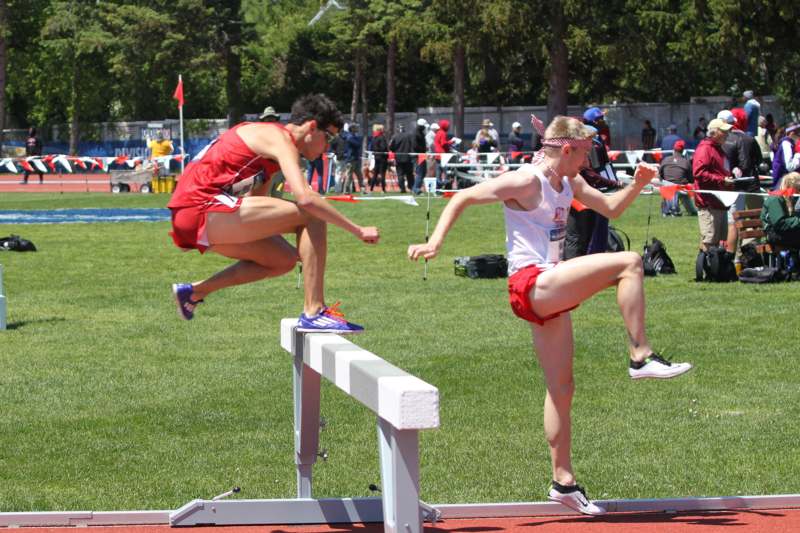 two men jumping over a hurdle