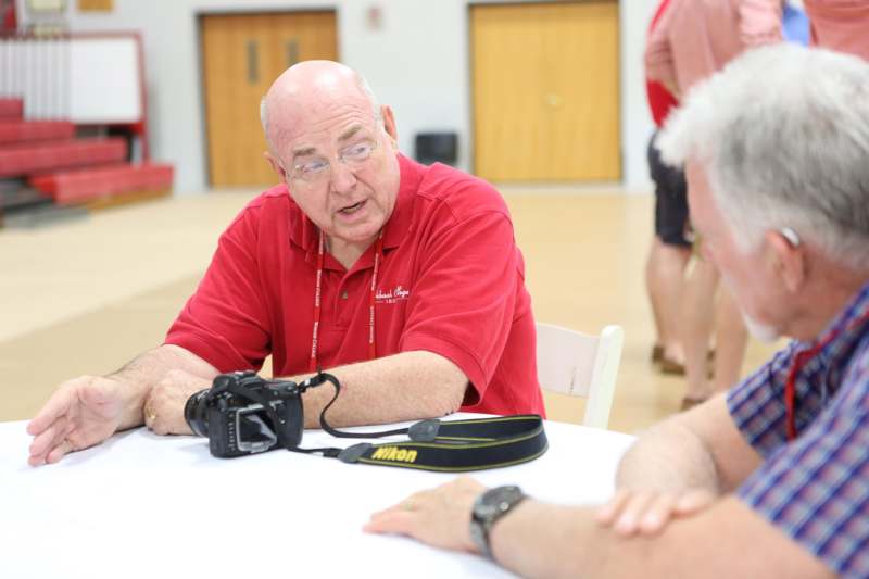 a man in red shirt sitting at a table with a camera