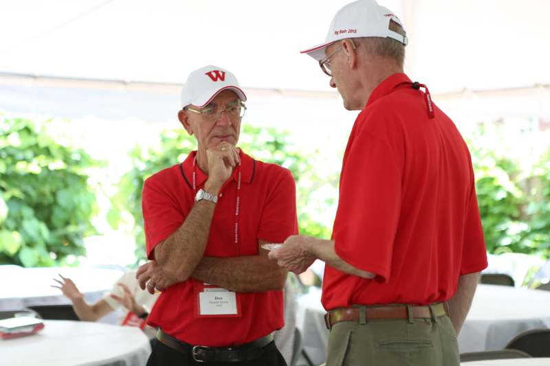 two men wearing red shirts and white hats