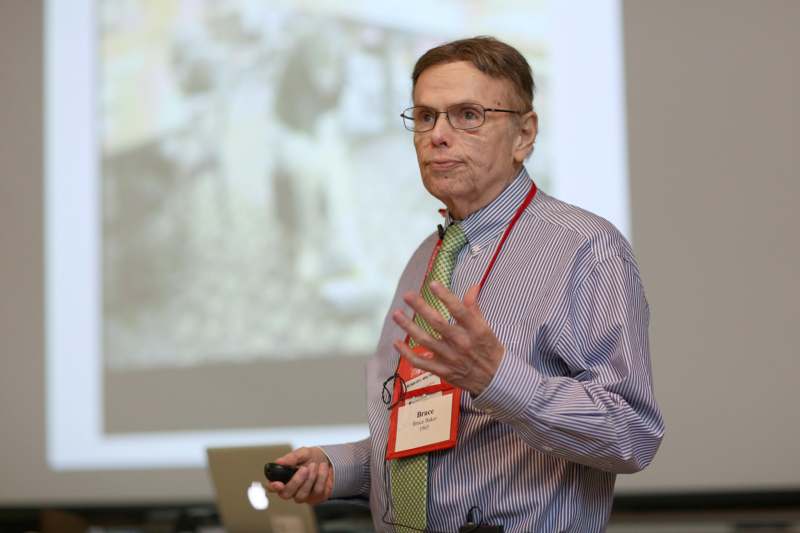 a man in a striped shirt and glasses giving a presentation