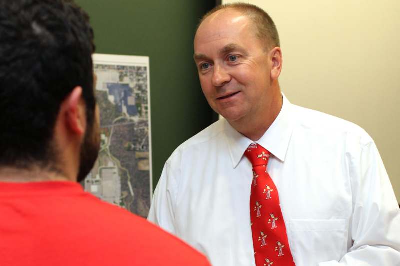 a man in a white shirt and red tie talking to another man