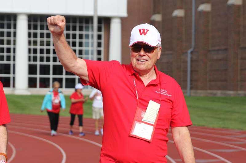 a man in a red shirt and white cap holding his fist up