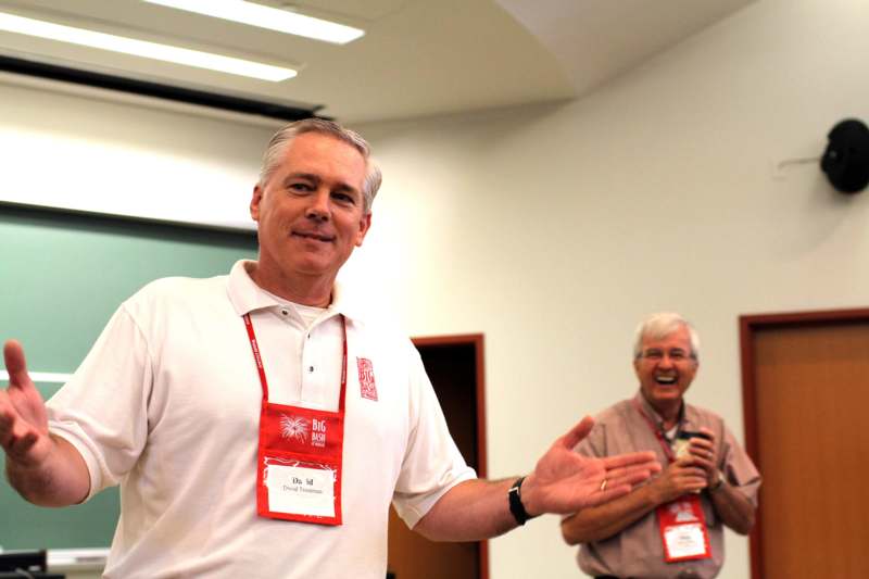 a man wearing a lanyard and a man smiling