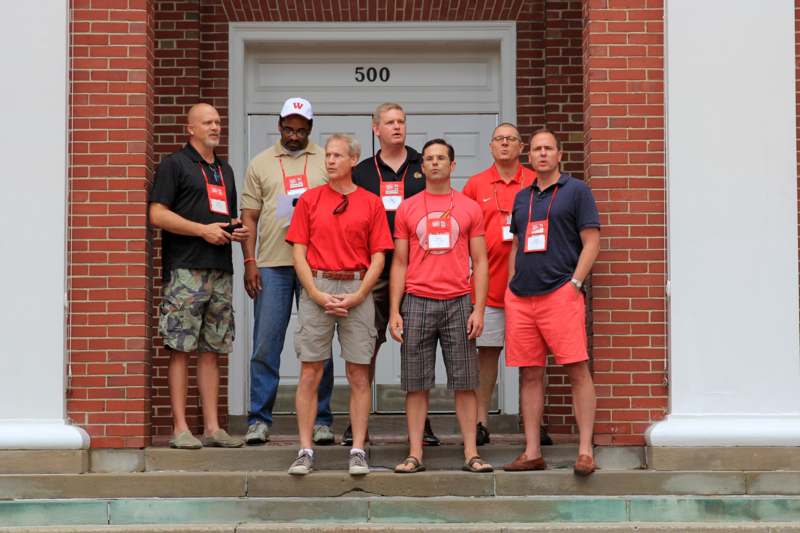 a group of men standing in front of a brick building