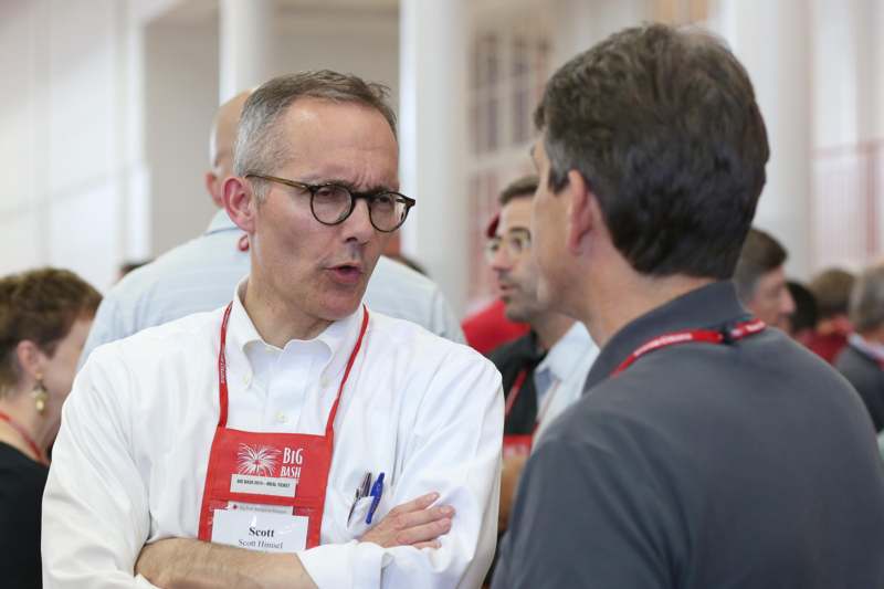 a man wearing glasses talking to another man