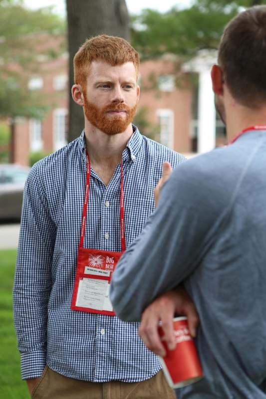 a man with red hair and a beard talking to another man