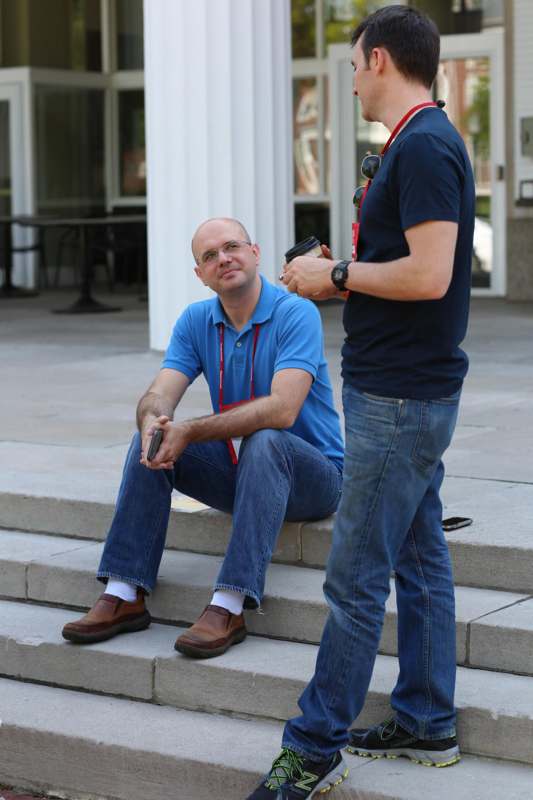 a man sitting on steps with a man holding a remote