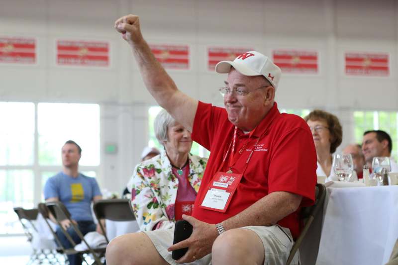 a man in a red shirt and white cap raising his fist
