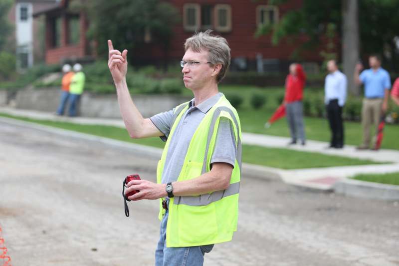 a man wearing a safety vest pointing up