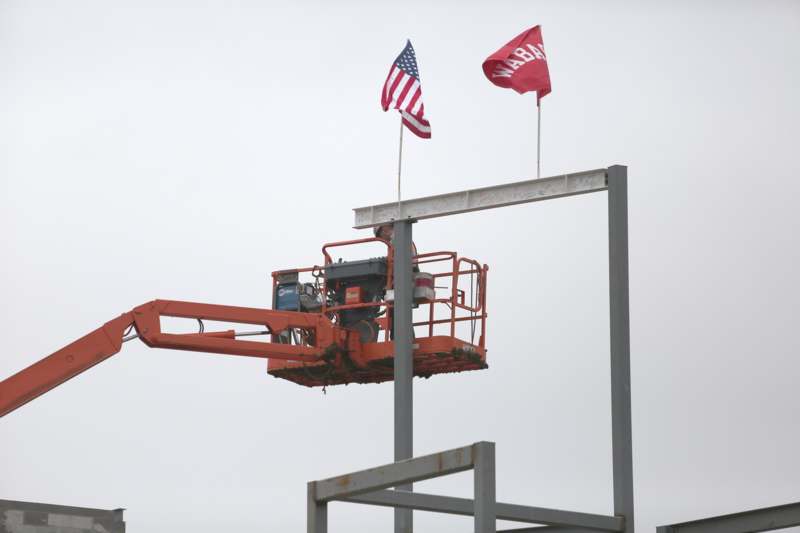 a man on a lift with two flags on top of a metal structure