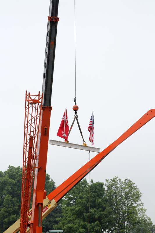 a crane lifting a metal beam with flags