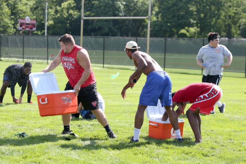 a group of men carrying coolers on a field