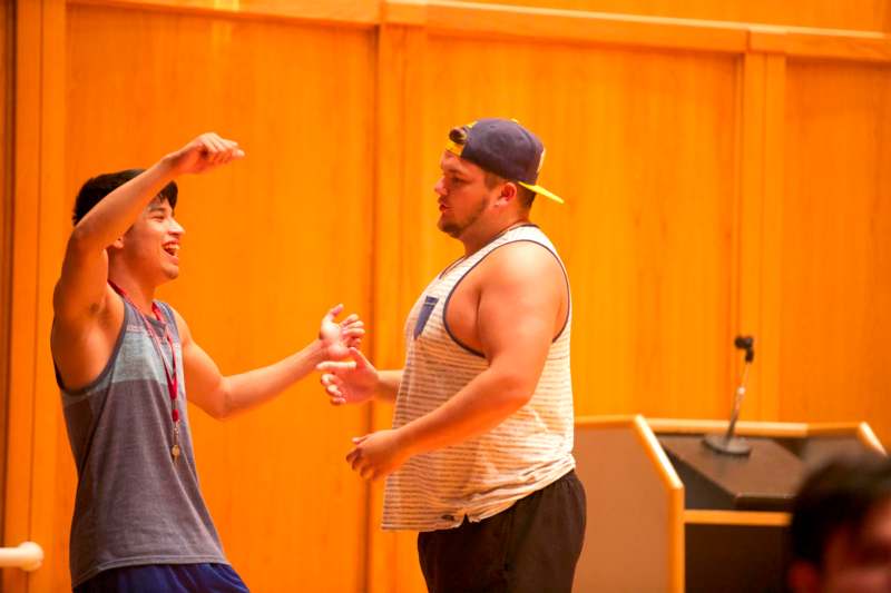 a man in a blue hat and tank top standing next to another man in a blue hat