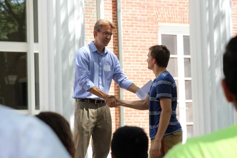 a man shaking hands with a man in front of a group of people