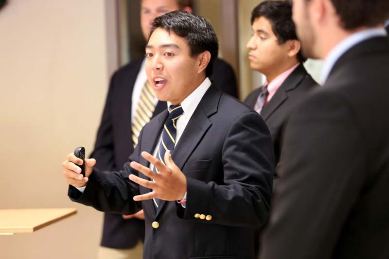 a man in a suit speaking to a group of men