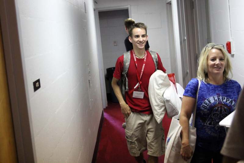 a man in a red shirt and backpack walking down a hallway
