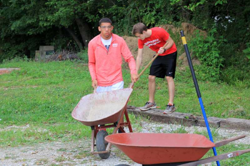 a couple of men pushing a wheelbarrow