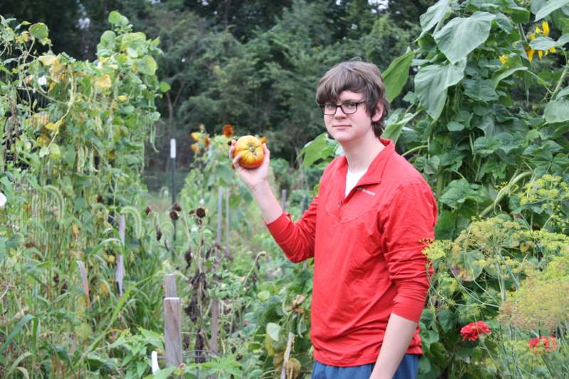 a man holding a tomato in a garden