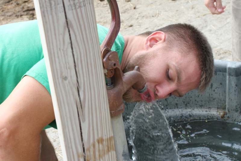a man drinking water from a water pump