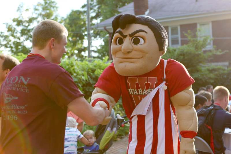 a man shaking hands with a person in a mascot garment
